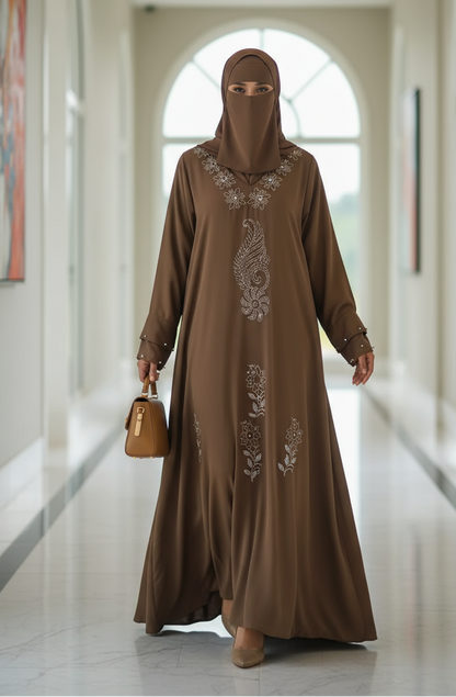 Woman in a brown embroidered abaya walking in a modern hallway.