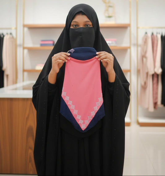 Person wearing a black hijab holding a pink and blue fabric in a store setting