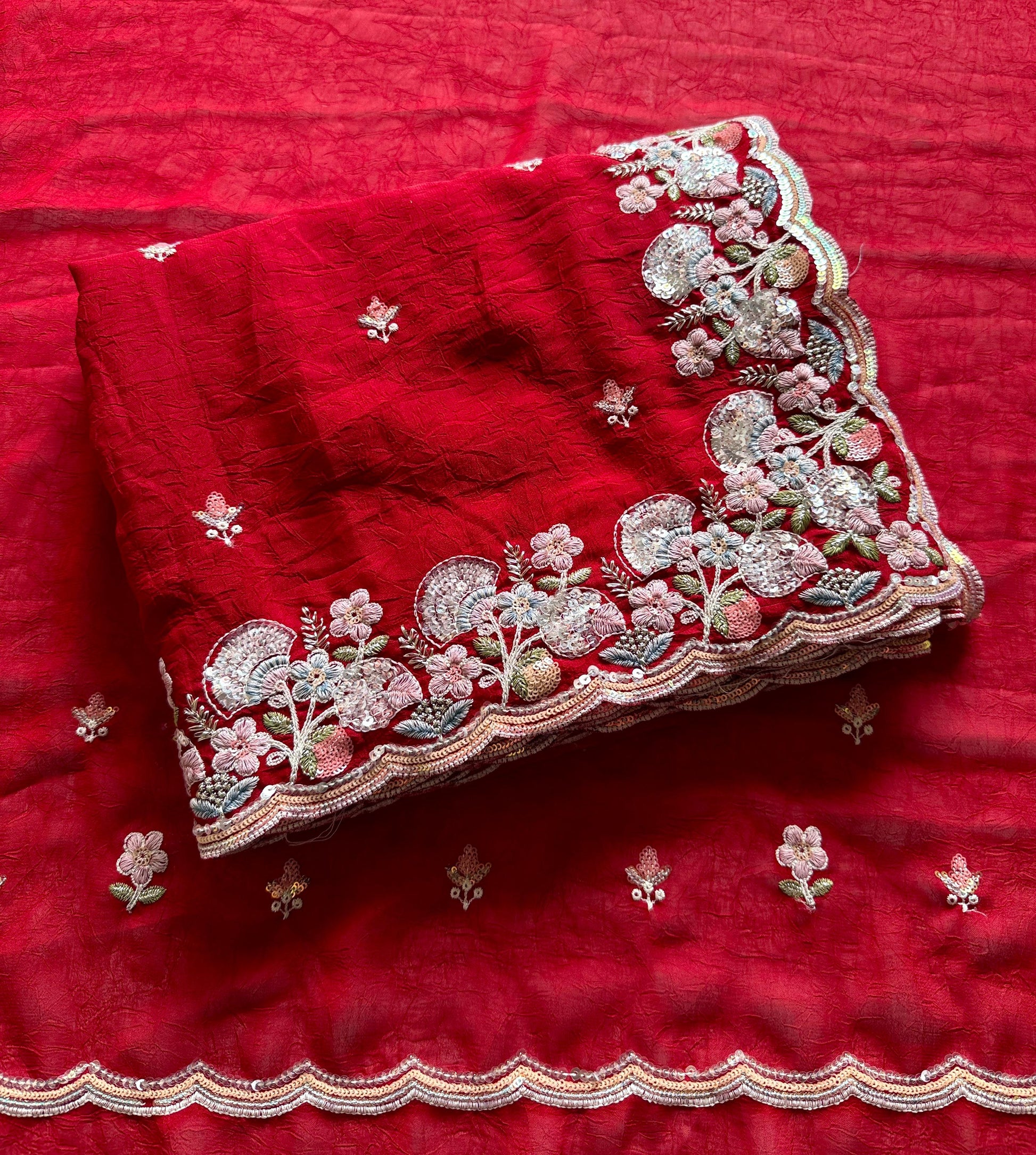 Soft crush silk saree with multicolor sequin embroidery and Red fabric with intricate white embroidery on a red background