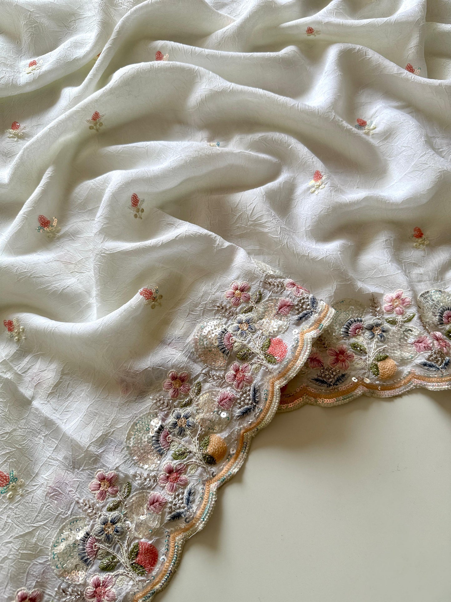 Close-up of a white embroidered fabric with floral patterns on a light background-Multicolor 4m sequin embroidery saree with soft lightweight fabric