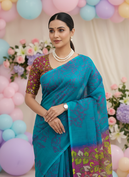 Soft linen cotton saree with simple classy drape – everyday ethnic wear-Woman in a blue saree with floral patterns standing in front of colorful balloons and flowers.