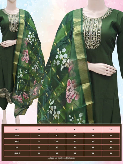 Green traditional outfit with floral patterns on a mannequin against a light pink background.